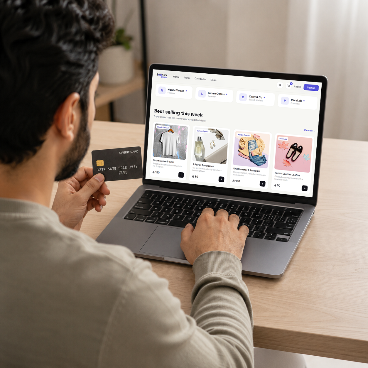 A shopper browsing the Bookify Stores marketplace on a laptop with a card in hand